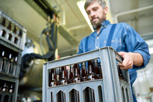 Eine Mehrwegkiste mit Bierflaschen wird getragen